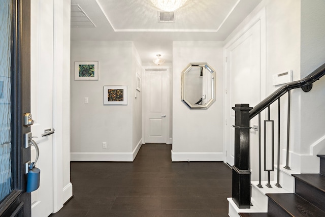 foyer featuring visible vents, baseboards, stairs, dark wood-style floors, and a tray ceiling