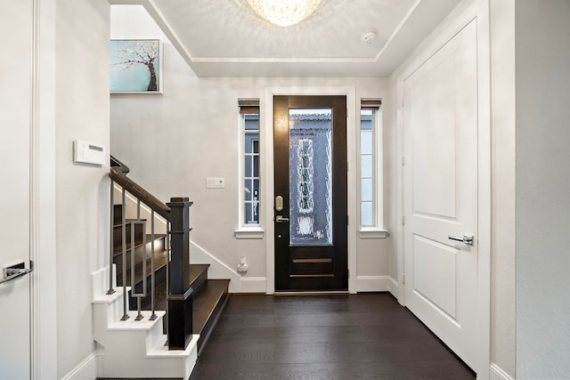 entryway featuring dark wood-style floors, a tray ceiling, stairs, and baseboards