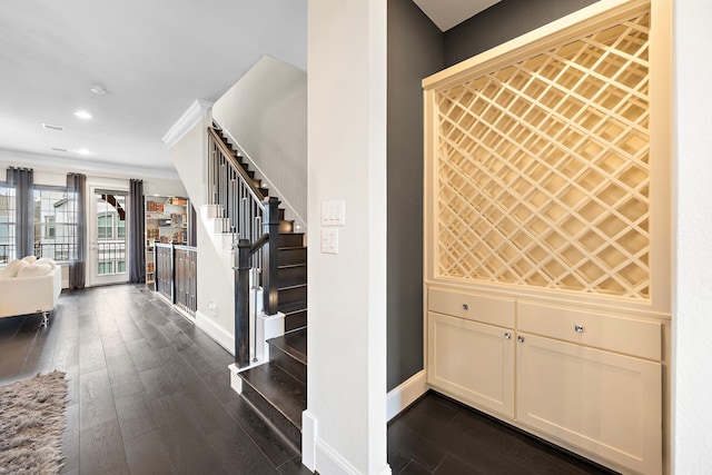 wine room featuring dark wood-style floors, recessed lighting, baseboards, and crown molding