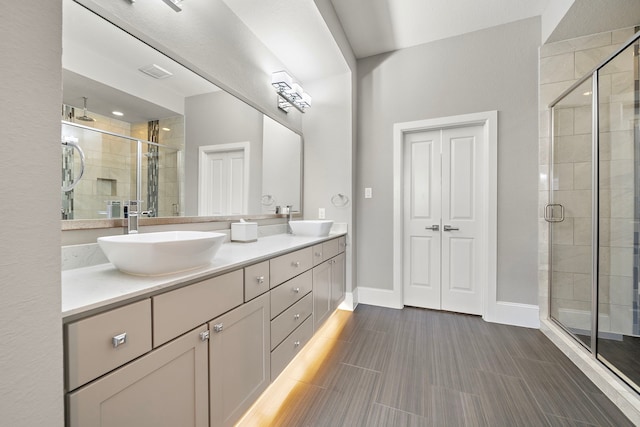 full bathroom featuring baseboards, double vanity, a sink, and a shower stall