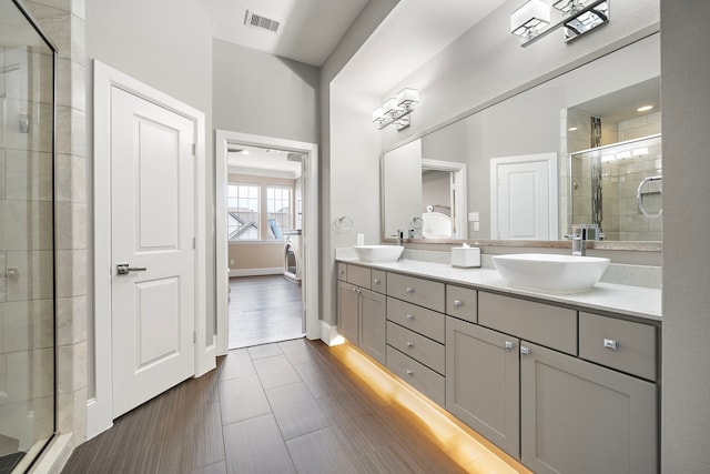 full bath featuring double vanity, a sink, visible vents, and a shower stall