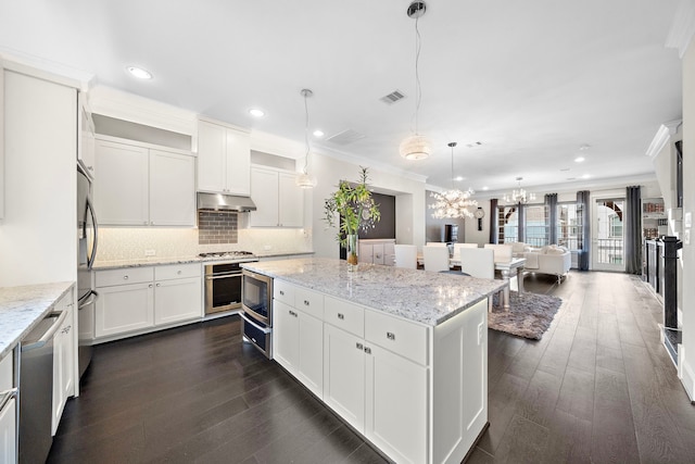 kitchen with stainless steel appliances, a center island, crown molding, and under cabinet range hood