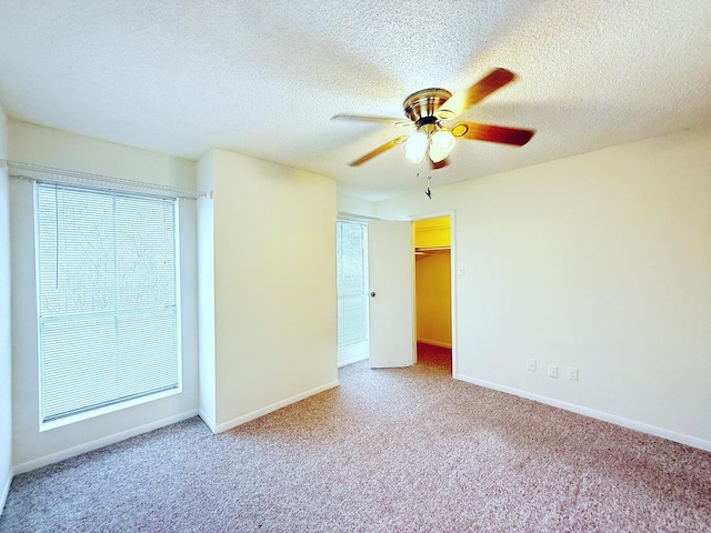 carpeted spare room featuring a ceiling fan, a textured ceiling, and baseboards