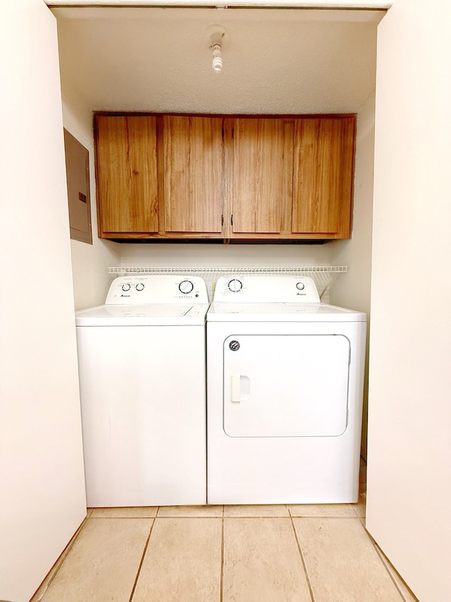 washroom featuring cabinet space, light tile patterned floors, and washer and dryer