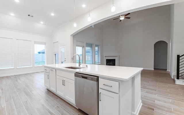 kitchen with wood finish floors, light countertops, open floor plan, a sink, and dishwasher