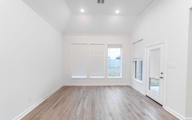 unfurnished room featuring crown molding, vaulted ceiling, light wood-style flooring, and baseboards