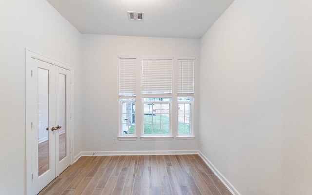 empty room featuring light wood-style flooring, visible vents, and baseboards