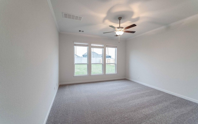 carpeted empty room featuring baseboards, a ceiling fan, visible vents, and crown molding