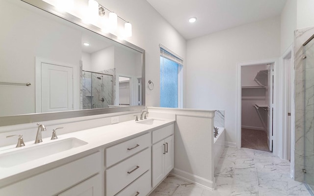 full bathroom featuring marble finish floor, a stall shower, a sink, and a walk in closet