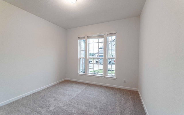 unfurnished room with baseboards and light colored carpet