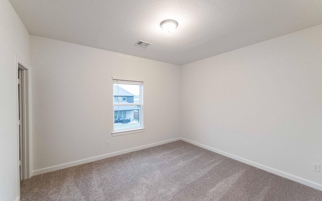 spare room with carpet floors, visible vents, and baseboards