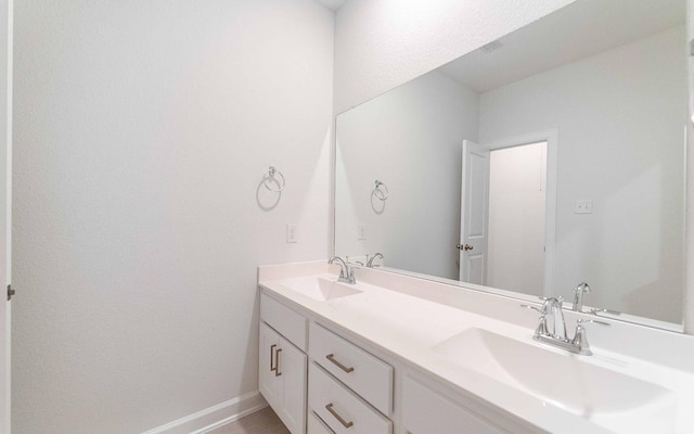 bathroom featuring double vanity, a sink, and baseboards