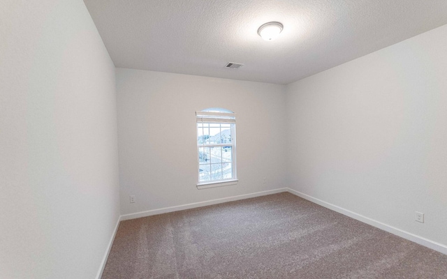 unfurnished room featuring carpet, visible vents, baseboards, and a textured ceiling