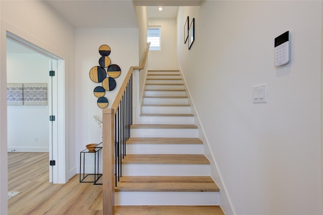 staircase featuring baseboards and wood finished floors