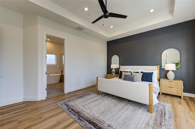 bedroom featuring light wood-type flooring, a raised ceiling, and visible vents