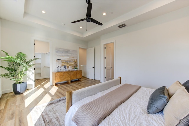 bedroom featuring a raised ceiling, visible vents, and light wood-style floors