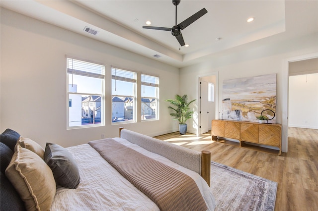 bedroom featuring recessed lighting, visible vents, baseboards, light wood-type flooring, and a raised ceiling