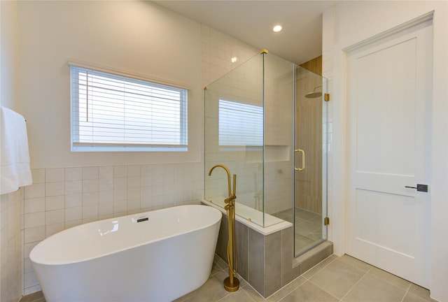 bathroom with a stall shower, tile patterned floors, a freestanding tub, tile walls, and recessed lighting