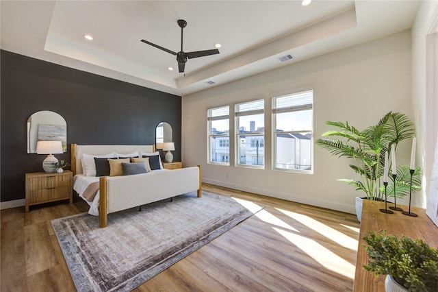 bedroom with a raised ceiling, visible vents, and baseboards