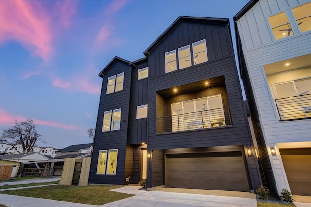 view of front of home featuring driveway, board and batten siding, an attached garage, and a balcony