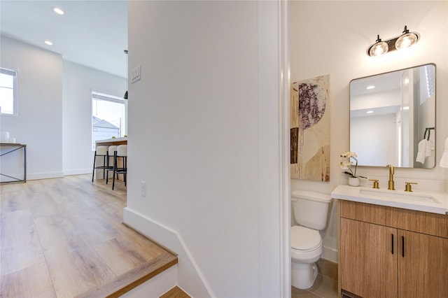 bathroom featuring toilet, vanity, a wealth of natural light, and recessed lighting