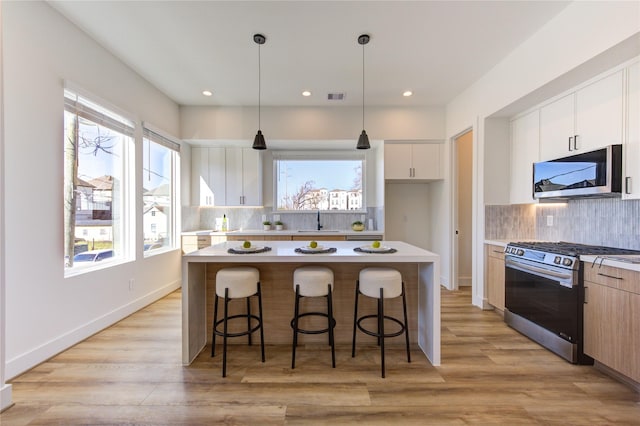 kitchen with a center island, light countertops, appliances with stainless steel finishes, light wood-style floors, and a sink