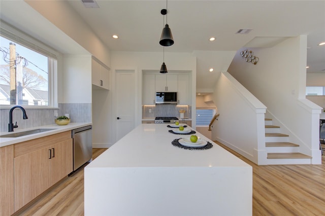 kitchen featuring a sink, visible vents, light countertops, appliances with stainless steel finishes, and light wood-type flooring