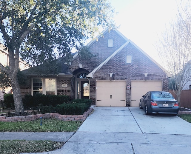 view of front of property featuring an attached garage, concrete driveway, and brick siding