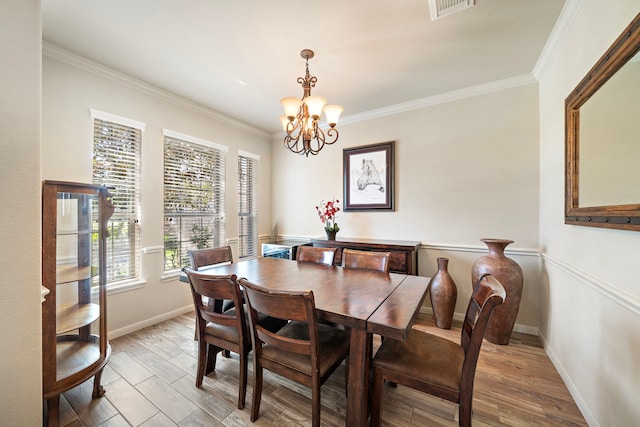 dining space with ornamental molding, a notable chandelier, and light wood finished floors