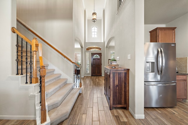 foyer featuring stairway, a high ceiling, baseboards, and wood finish floors