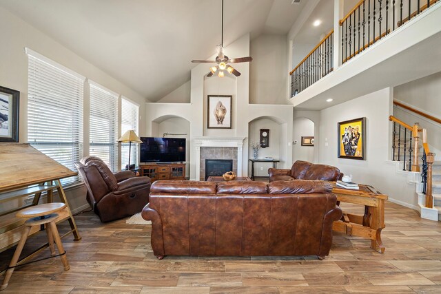 living room featuring stairs, light wood-type flooring, a fireplace, and baseboards