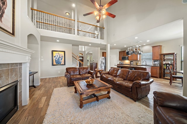 living area with light wood finished floors, stairway, a fireplace, and baseboards