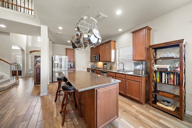 kitchen featuring brown cabinetry, a kitchen island, stainless steel appliances, and light wood-style floors