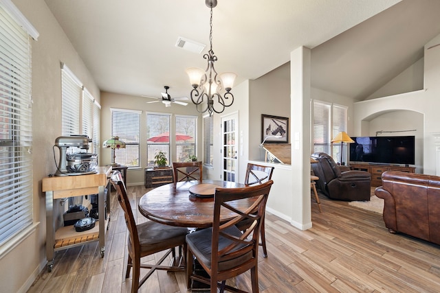 dining space with lofted ceiling, visible vents, light wood-style flooring, an inviting chandelier, and baseboards