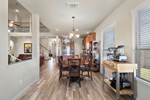 dining space featuring light wood finished floors, visible vents, arched walkways, and baseboards