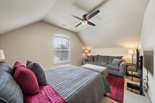 carpeted bedroom with a ceiling fan, visible vents, vaulted ceiling, and a textured ceiling