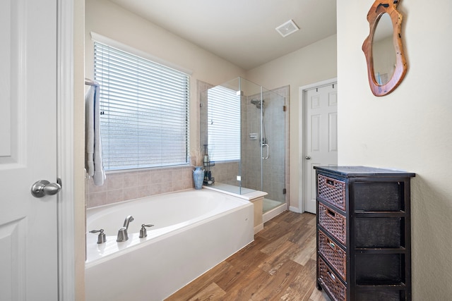 bathroom with visible vents, a garden tub, a shower stall, and wood finished floors