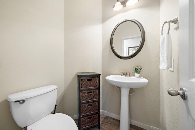 bathroom with baseboards, a sink, toilet, and wood finished floors