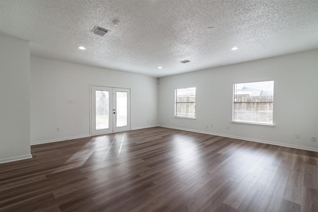 spare room featuring french doors, dark wood finished floors, recessed lighting, a textured ceiling, and baseboards