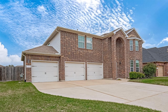 traditional home with driveway, fence, a front lawn, and brick siding