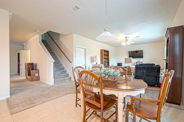 dining room featuring ceiling fan, light carpet, visible vents, baseboards, and stairs