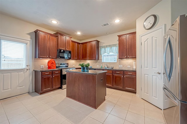 kitchen with stainless steel appliances, dark countertops, a sink, and visible vents