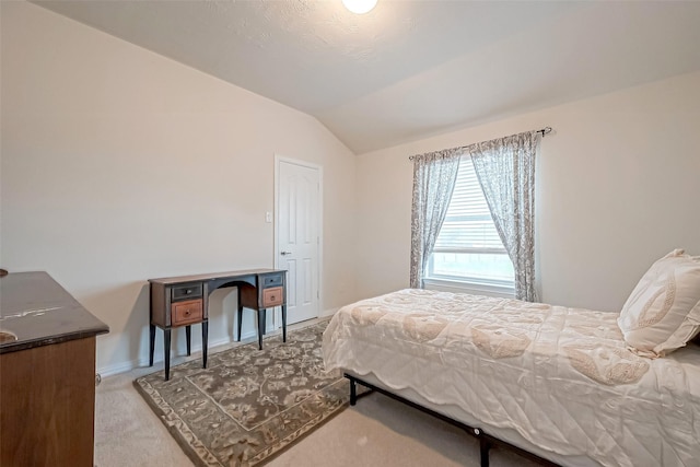 bedroom with light colored carpet, vaulted ceiling, and baseboards