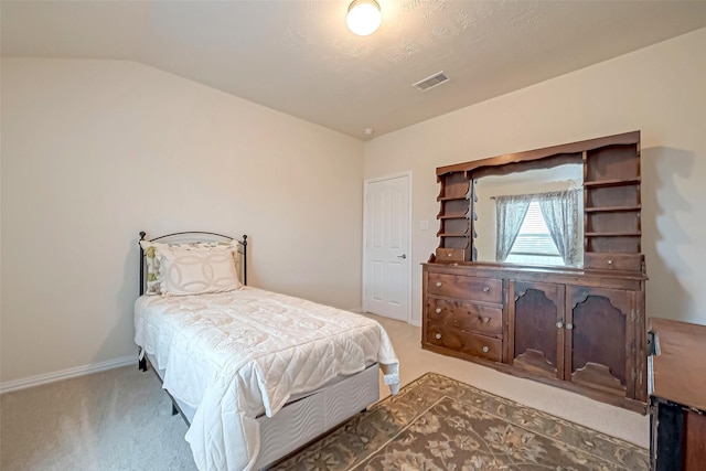 carpeted bedroom featuring vaulted ceiling and visible vents