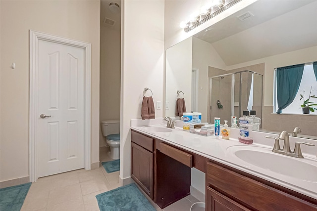 bathroom featuring a stall shower, double vanity, a sink, and tile patterned floors