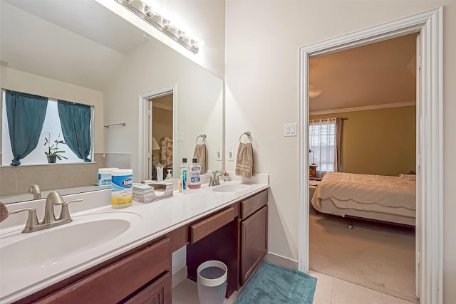 ensuite bathroom with ensuite bathroom, double vanity, tile patterned flooring, and a sink