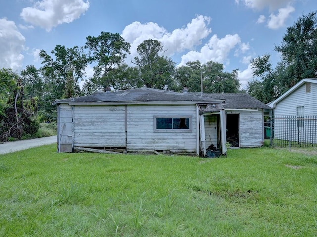 back of house featuring a lawn and fence