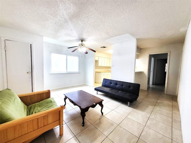 living area featuring visible vents, a ceiling fan, light tile patterned flooring, a textured ceiling, and baseboards