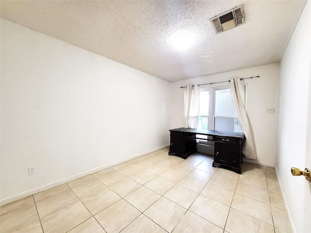 unfurnished office with visible vents, a textured ceiling, baseboards, and light tile patterned floors