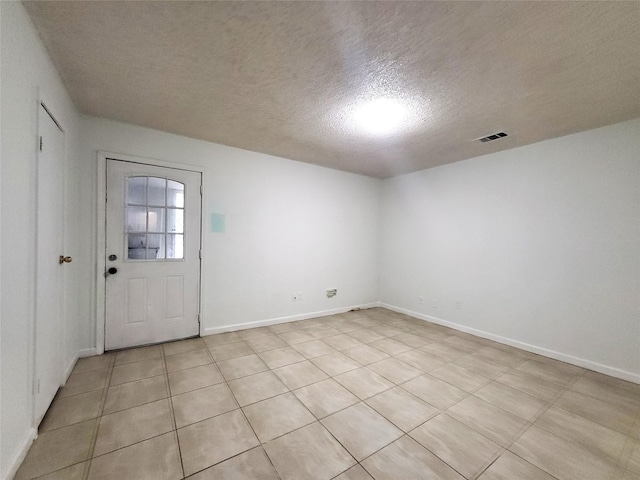 spare room featuring visible vents, a textured ceiling, and baseboards